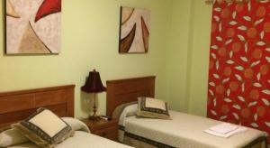een slaapkamer met 2 bedden en een rood gordijn bij Hostal el mirador in Higuera de Llerena