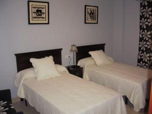2 bedden in een hotelkamer met witte lakens bij Hostal el mirador in Higuera de Llerena