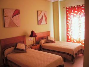 een hotelkamer met 2 bedden en een raam bij Hostal el mirador in Higuera de Llerena
