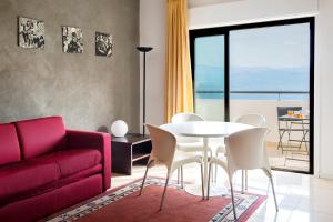 sala de estar con sofá rojo, mesa y sillas en Residence Annunziata, en Messina