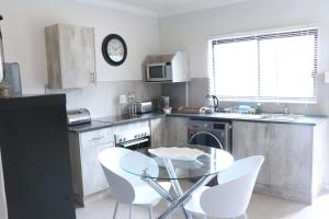a kitchen with a table and white chairs in it at Millennium Body Guards Guesthouse in Hartbeespoort