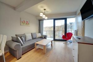 a living room with a couch and a red chair at Apartamenty EverySky - Wilcza 3F-1 in Karpacz
