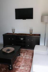 een woonkamer met een bank en een flatscreen-tv bij Millennium Body Guards Guesthouse in Hartbeespoort