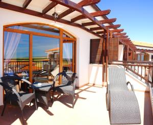 eine Terrasse mit Stühlen und Tischen auf einem Balkon in der Unterkunft The Vineyards Boutique Hotel & SPA in Aheloy