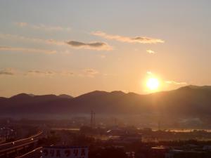 um pôr-do-sol sobre uma cidade com montanhas ao fundo em Hotel Route-Inn Aomori Chuo Inter em Aomori