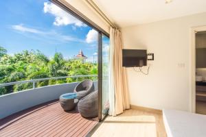 a room with a balcony with a bed and a tv at Baan Suwantawe in Phuket