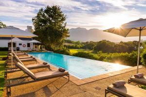 a swimming pool with lounge chairs and umbrellas at De Zalze Lodge in Stellenbosch