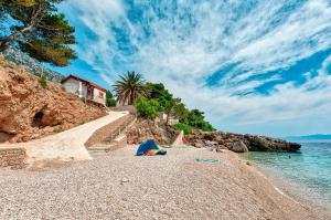 a beach with people laying on the sand and the water at Villa Gloria in Potomje