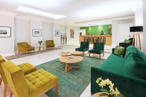 a living room with a green couch and chairs at Hollow on the Square City Hotel in Cape Town