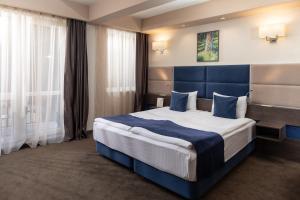 a hotel room with a large bed with blue pillows at Belfort Hotel in Braşov