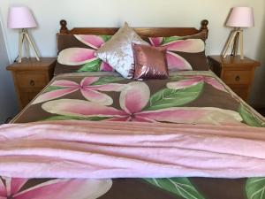CurrarongにあるBull Ray Beach Houseのピンクの花が飾られたベッド(ランプ2つ付)