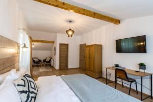 Schlafzimmer mit einem Bett, einem Schreibtisch und einem TV in der Unterkunft Drachenhaus Urban Villa in Braşov