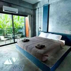 a bedroom with a large bed and a large window at Baan Bida in Krabi town