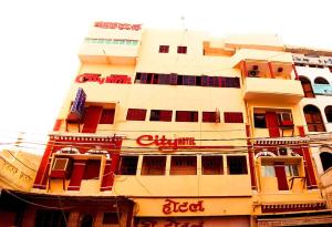 um edifício alto com janelas vermelhas no lado em City Hotel em Allahabad
