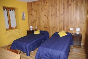 Habitación con 2 camas con sábanas azules y paredes de madera. en La Cabaña, en Canfranc