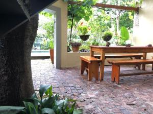 a patio with a table and benches and a tree at 10 Alexander B&B in Stellenbosch