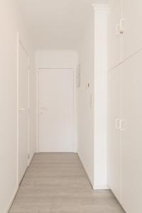 an empty corridor with white doors and a wooden floor at Apartment Green Garden in Middelkerke