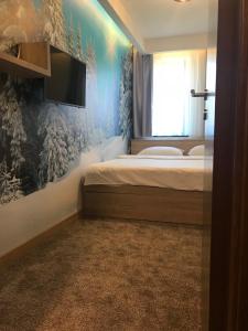 a bedroom with a bed and a tv on a wall at Apartmani Astoria 1 in Jahorina
