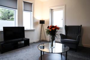 ein Wohnzimmer mit einer Vase mit Blumen auf einem Tisch in der Unterkunft Baron View Apartment in Paisley