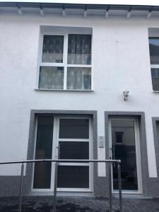 biały budynek z dwoma oknami i drzwiami w obiekcie Apartment 4 Rent w mieście Bochum