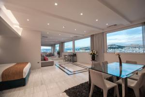 a bedroom with a bed and a dining room with a glass table at Athenaeum Grand Hotel in Athens