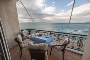 een tafel en stoelen op een balkon met uitzicht op de oceaan bij Amazing condo by the beach in Loutraki