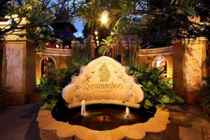 a bench in a garden with a fountain in the middle at Sawasdee Village in Kata Beach