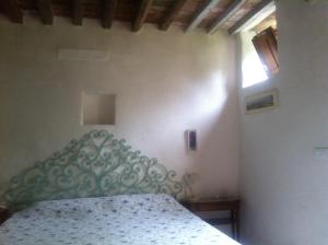 - une chambre avec un lit doté d'une tête de lit verte et d'une fenêtre dans l'établissement Antico Rustico fra vigneti e uliveti, à Corsanico-Bargecchia