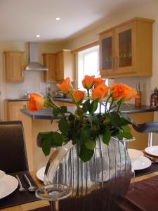a vase with orange roses on a table in a kitchen at Ardmullen in Kenmare