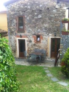- un bâtiment en pierre avec une table et des chaises devant dans l'établissement Antico Rustico fra vigneti e uliveti, à Corsanico-Bargecchia