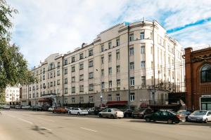 un gran edificio blanco con coches estacionados frente a él en Tsentralny by USTA Hotels, en Yekaterinburg