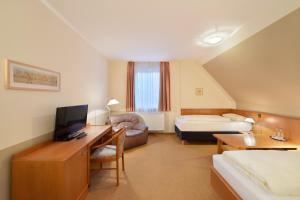 a hotel room with a bed and a desk with a television at meinHotel in Hamburg