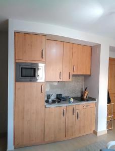 a kitchen with wooden cabinets and a microwave at Snow in Miramar in Sierra Nevada