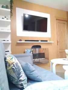 a living room with a blue couch and a flat screen tv at Snow in Miramar in Sierra Nevada