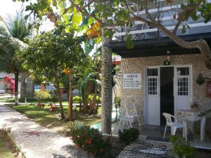 a building with a table and chairs in a yard at Chalé 01 em Maragogi Brasil Maragogi in Maragogi