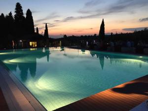 a large swimming pool with a sunset in the background at Hapimag Resort Tonda in Montaione