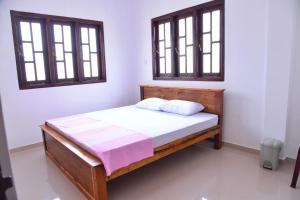 a bed in a room with two windows at Roshan's Guest House in Hikkaduwa