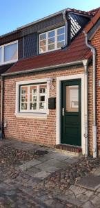 a brick house with a green door and windows at Ein kleines Haus in Fehmarn