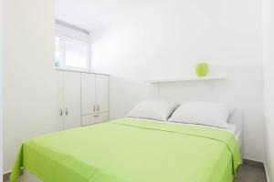 Dormitorio blanco con cama verde y ventana en Stylish Centre Apartments, en Zadar