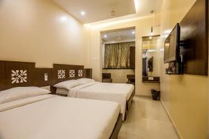 a hotel room with two beds and a flat screen tv at City Guest House - Dadar in Mumbai