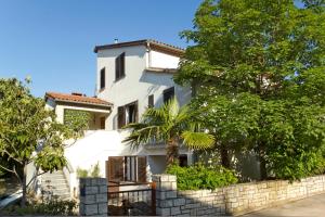 a white house with a palm tree in front of it at Apartments Mladenka in Poreč