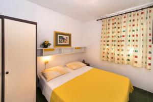 sypialnia z żółtym łóżkiem i oknem w obiekcie Apartments Mladenka w Poreču