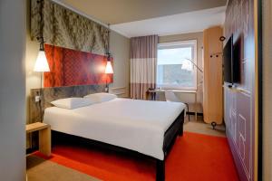 a hotel room with a large white bed and a window at Ibis Münster City in Münster