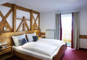 a bedroom with a large bed with a wooden headboard at JUFA Alpenhotel Saalbach in Saalbach Hinterglemm