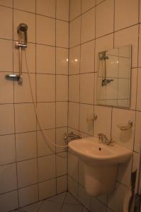 a white tiled bathroom with a sink and a shower at хотел Европа in Shumen