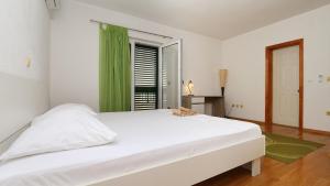 a white bedroom with a large bed and a window at House Lipo in Makarska