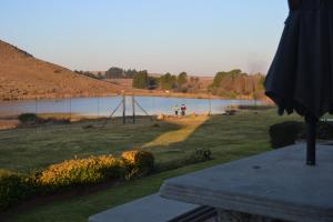 Una vista de un lago con dos personas en un columpio en Fox & Squirrel, en Dullstroom
