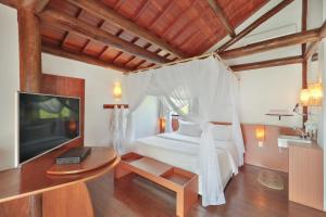 um quarto com uma cama branca e uma televisão em Teju-Açu Ecopousada em Fernando de Noronha