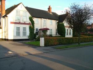 a white house with a black roof on a street at The Beaumont Accommodation in Louth