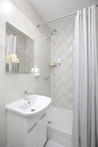 a white bathroom with a sink and a shower curtain at Hotel Sova in Krasnoyarsk